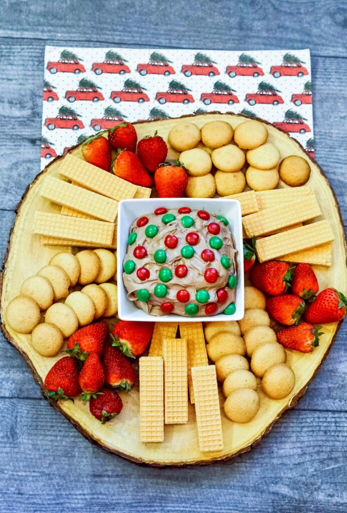 Brownie Batter Dip on a wooden board with cookies, crackers and strawberries. 
