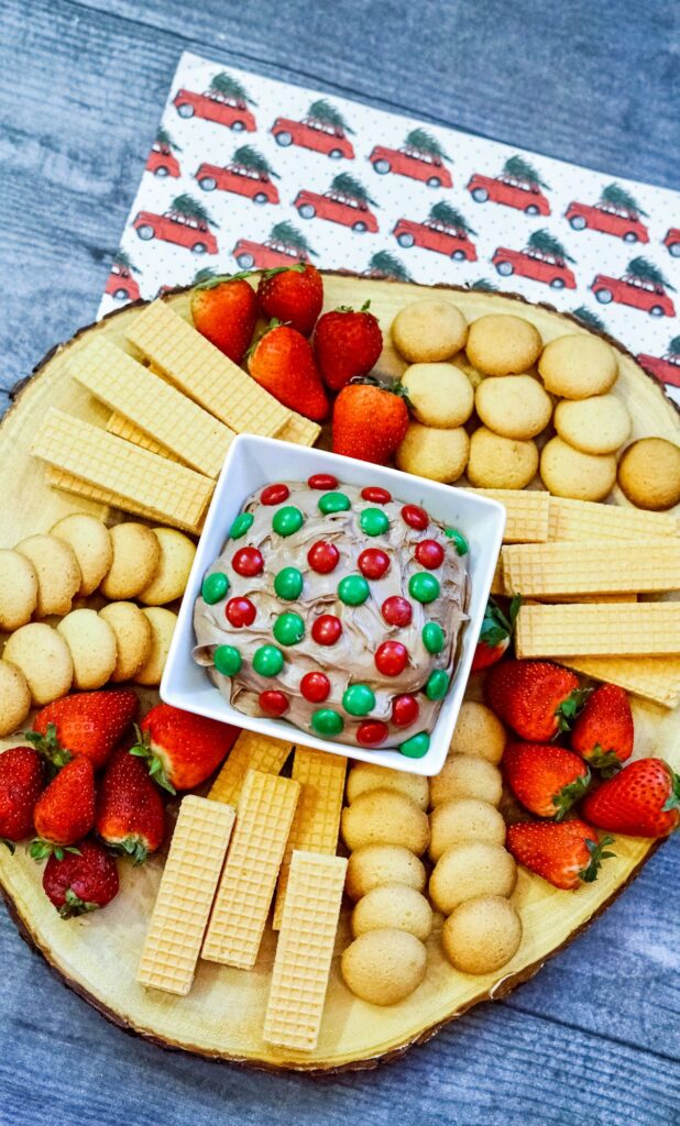 Brownie Batter Dip on a wooden board with cookies, crackers and strawberries. 