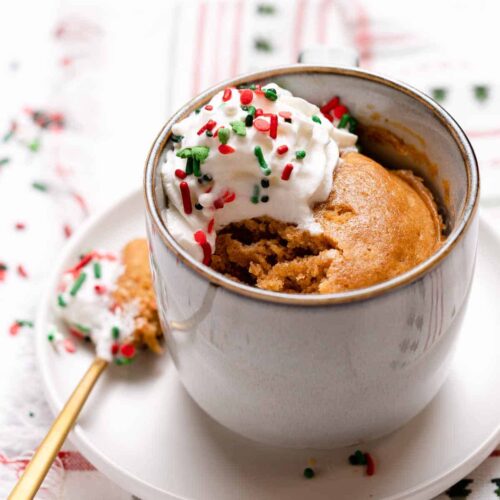 Gingerbread mug cake with whipped cream and festive sprinkles