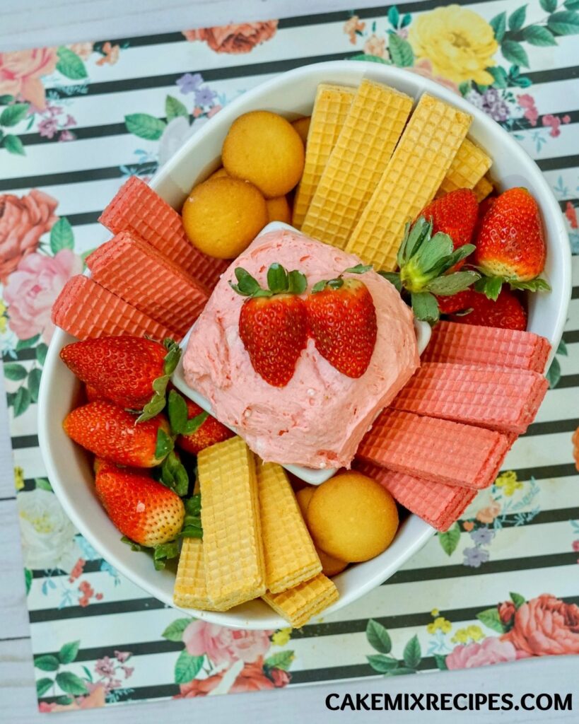 Strawberry Cake Batter Dip on a plate surrounded with fresh strawberries, wafer and cookies. 