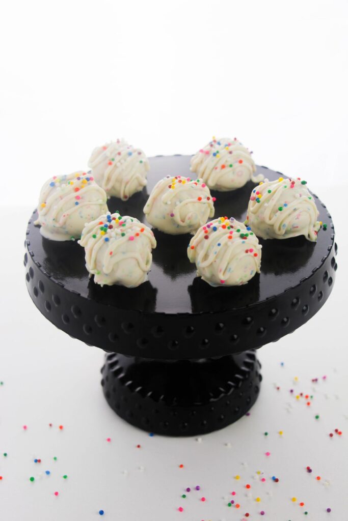 Sugar Cookie Truffles topped with funfetti sprinkles on a cake plate.