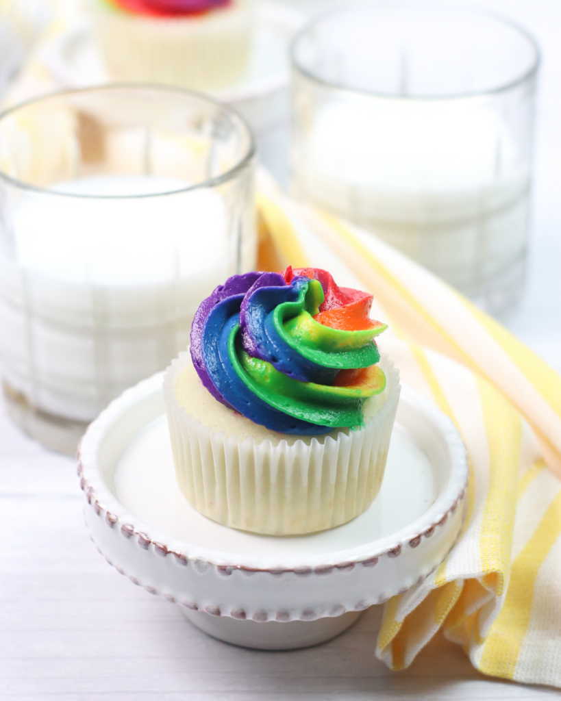 Vanilla Filled Cupcakes on a cupcake stand with glass of milk on the side.