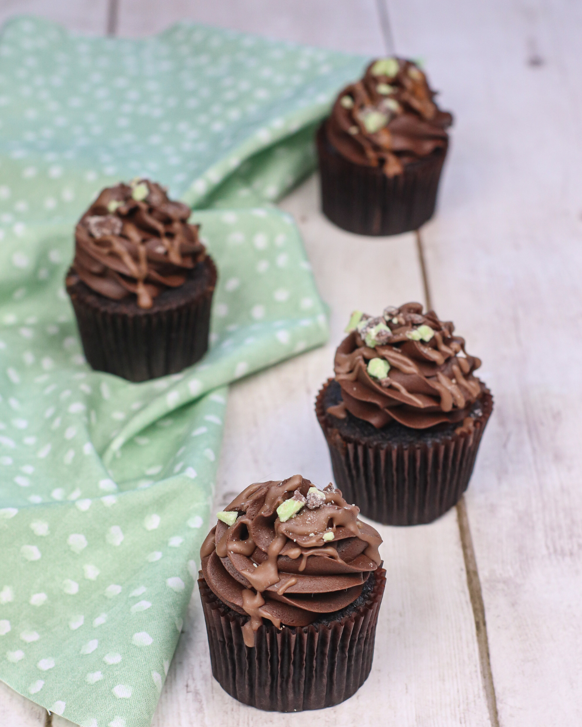 mint chocolate cupcakes on a wood table and green and white cloth.