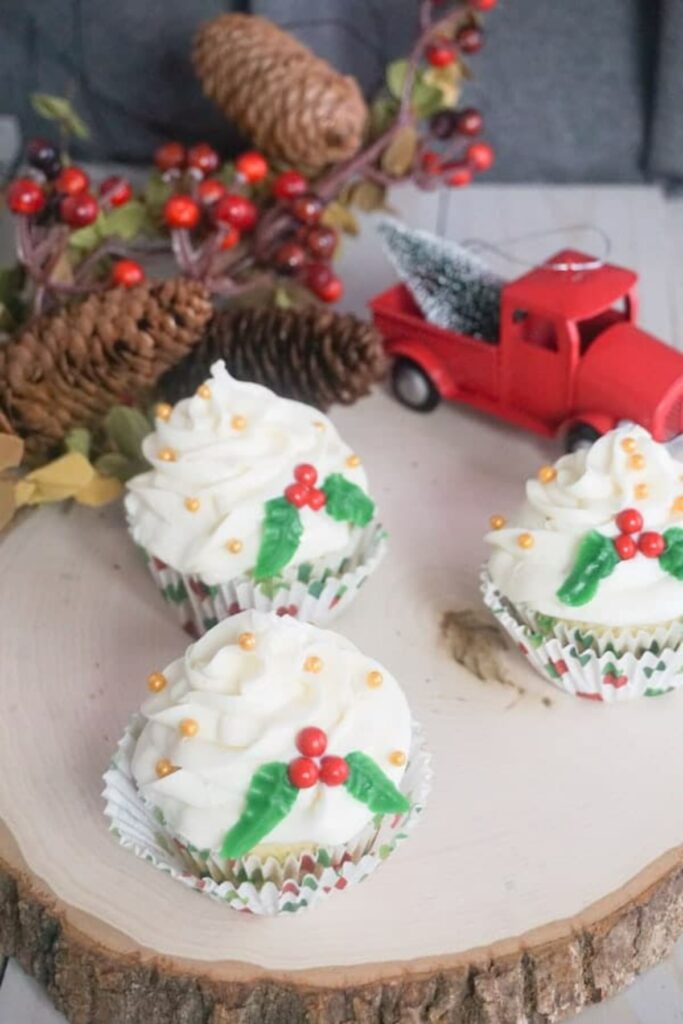 Christmas Holly Cupcakes next to a toy red truck and pinecones.