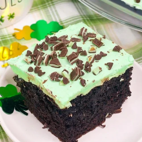 Chocolate poke cake with green icing topped with chocolate mint crumble