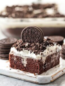 Layered oreo poke cake topped with an oreo cookie