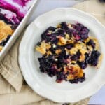 A white plate with blueberry cobbler with cake mix.