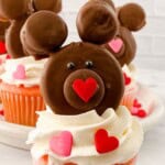 A brown teddy bear on top of white frosting.