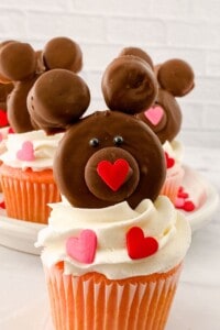 A brown teddy bear on top of white frosting.