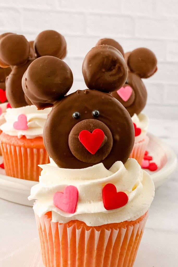 A brown teddy bear on top of white frosting.