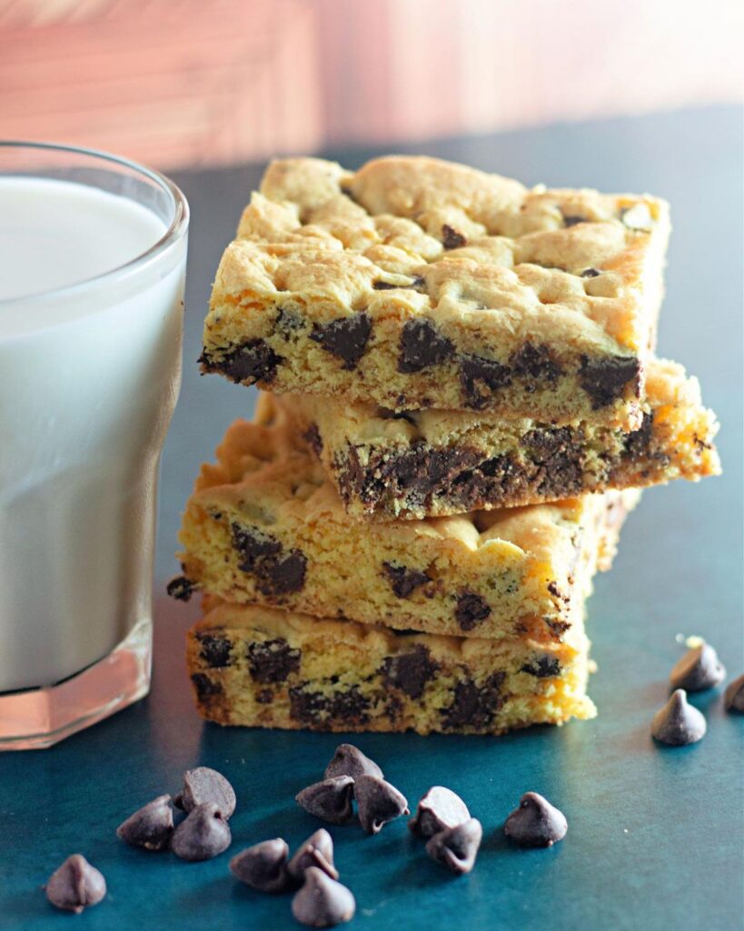 A stack of Chocolate Chip Cake Mix Cookie Bars  on a table next to a glass of milk.