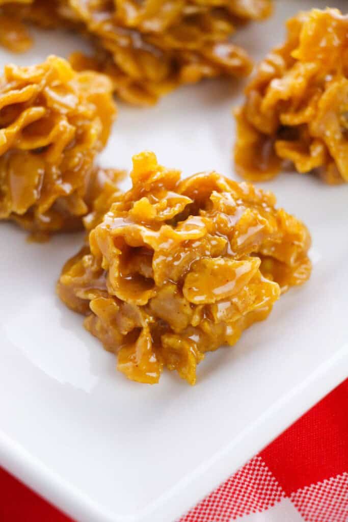 A white plate with a cornflake cookie on it.