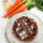 A plate of the carrot cake waffles next to a bnch of carrots.