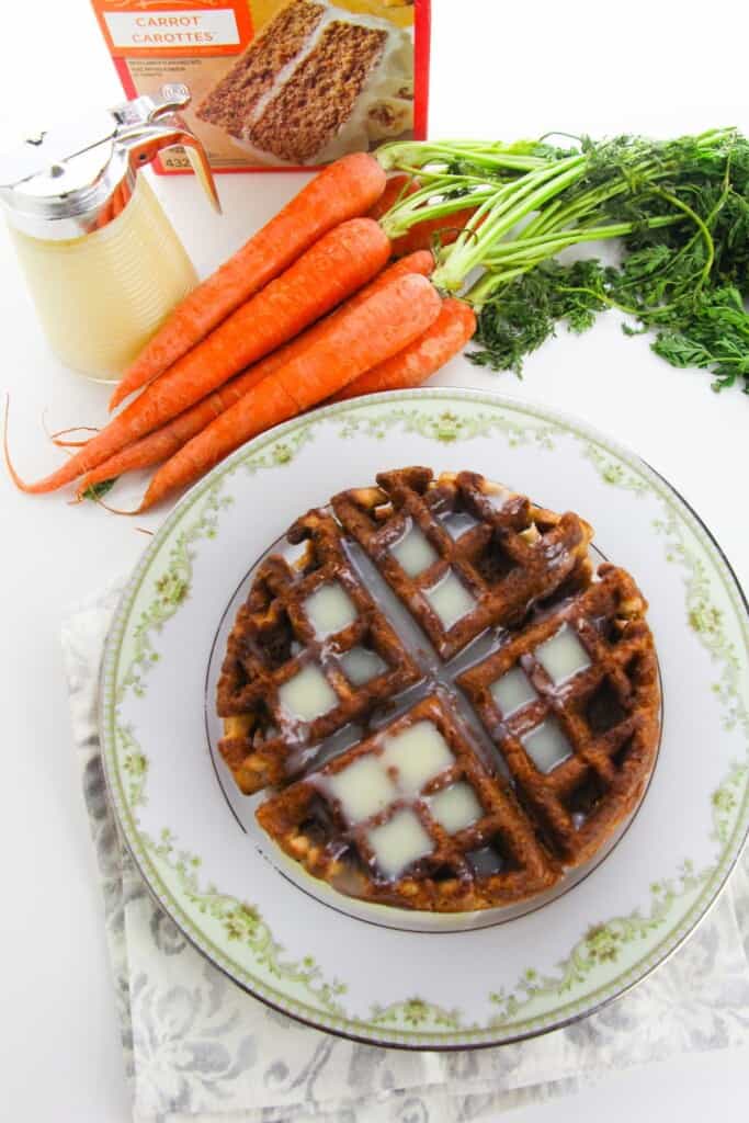 A plate of the carrot cake waffles next to a bnch of carrots.