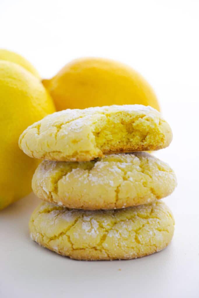 A stack of lemon cookies with a bite taken out of one.