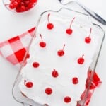 A cake pan with whipped cream and cherries on top.