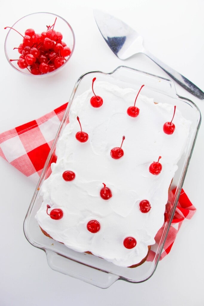 A cake pan with whipped cream and cherries on top.