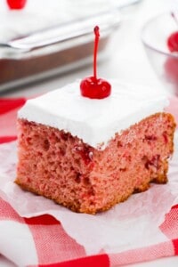 A slice of cherry almond cake on a red and white check cloth.