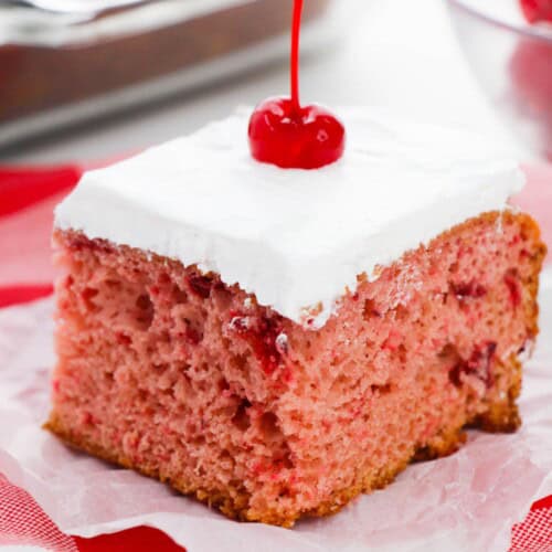 A slice of cherry almond cake on a red and white check cloth.