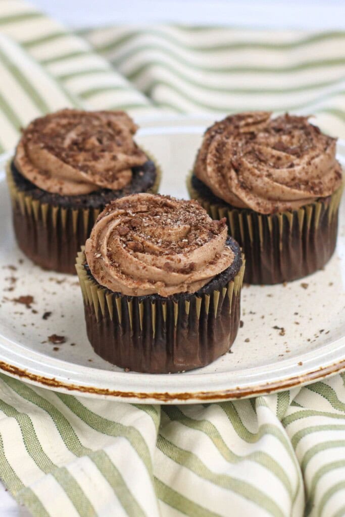 A plate with three cocoa pebbles cupcakes.