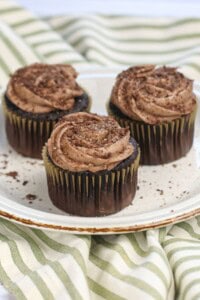 Three cocoa pebbles cupcakes on a plate.