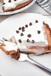A fork of the chocolate pudding cream pie on a white plate.