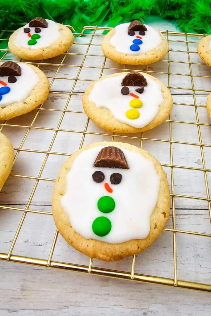 A melting snowman cookie with a top hat and green buttons.