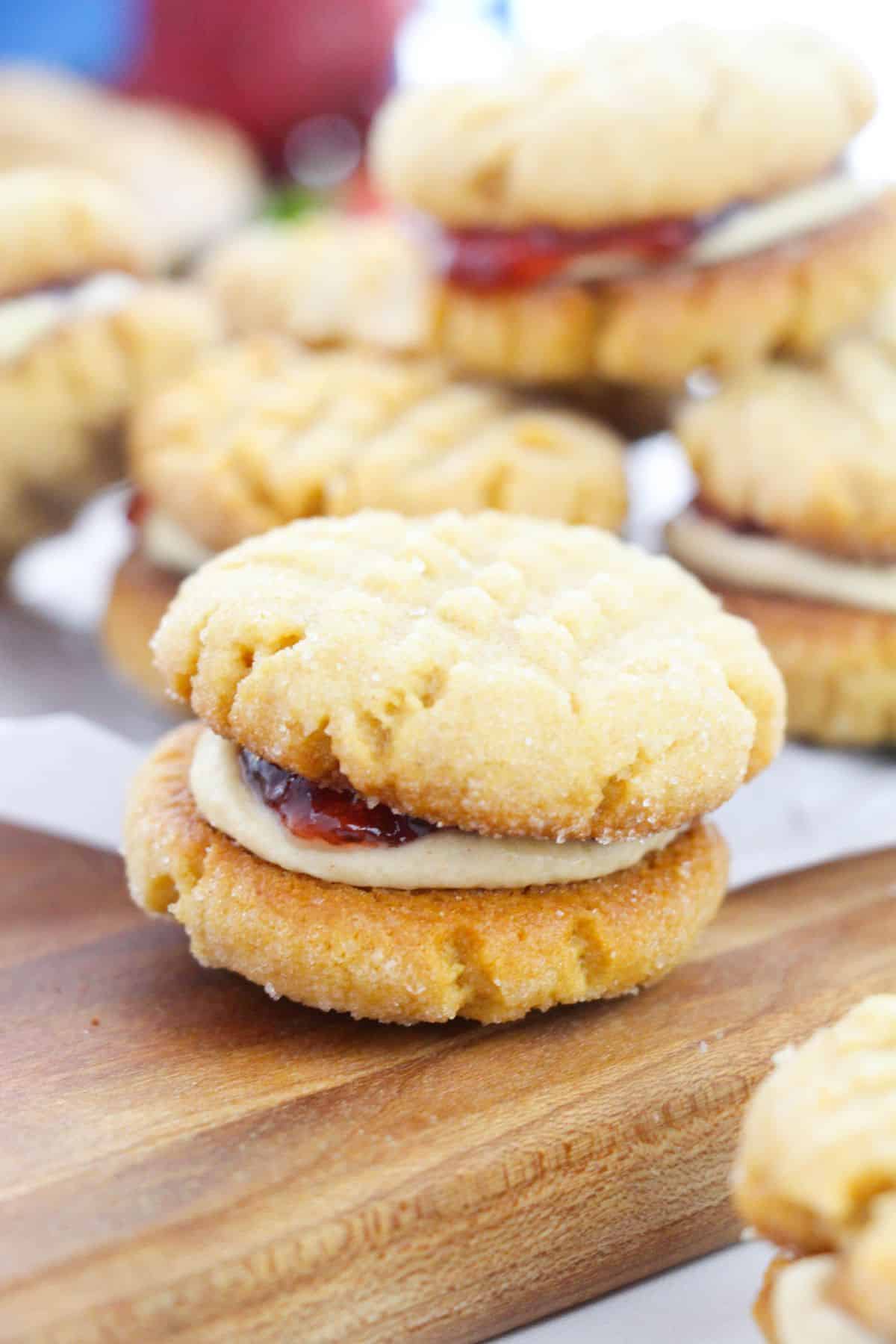 A peanut butter sandwich cookie on a wooden cutting board.